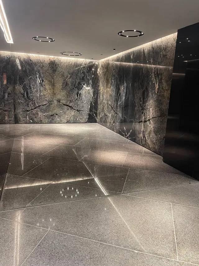 Lobby with dark veined marble walls and a polished floor