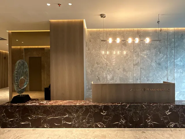 Reception with a dark marble counter and a pale stone wall